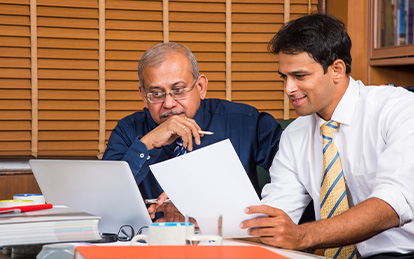 Two men sitting at a desk discussing business strategy.