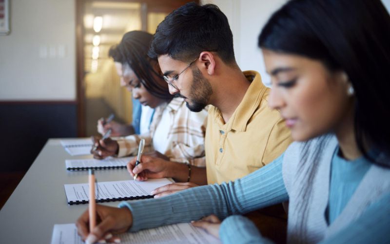 a group of students diligently writing notes while engaged in a classroom discussion