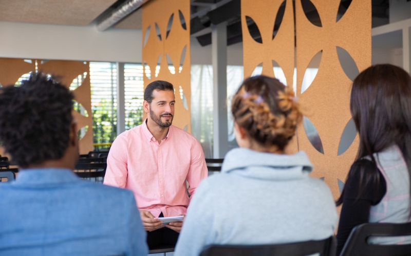 a man is taking personality development coaching classes of three other people