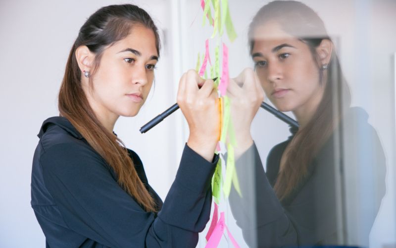 a woman is writing on a white board