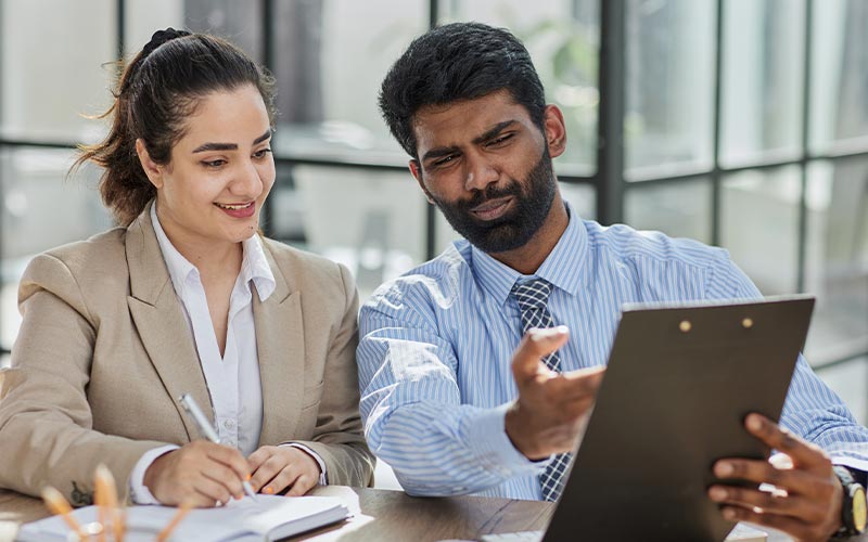 two professionals reviewing a document on a laptop, engaged in a business discussion