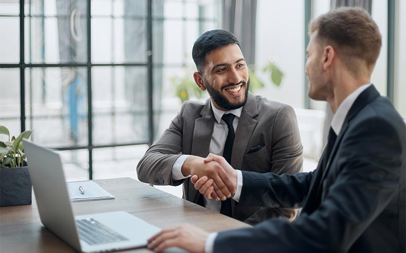 two professionals shaking hands in an office, symbolizing a successful business deal