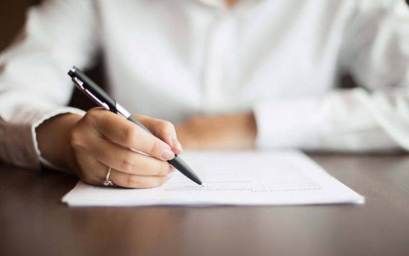 Someone using a pen to write on paper.